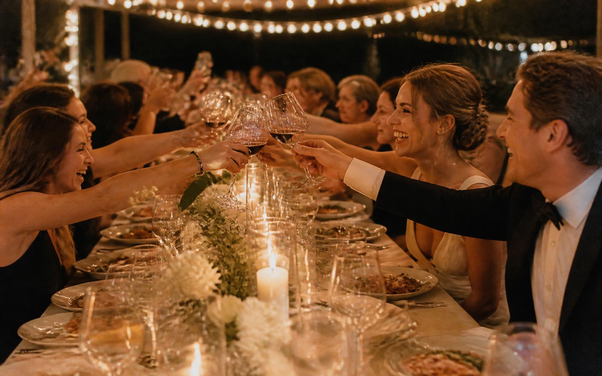 Guests raising glasses at a long candlelit BRAVA table